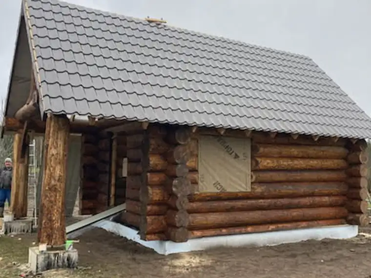 Ümarpalkhoone kivikatuse ja betoonsoklil seisva seinaga